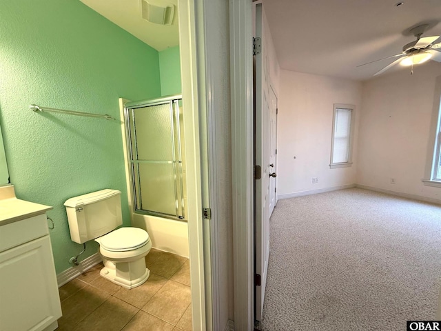 bathroom featuring baseboards, toilet, ceiling fan, combined bath / shower with glass door, and vanity