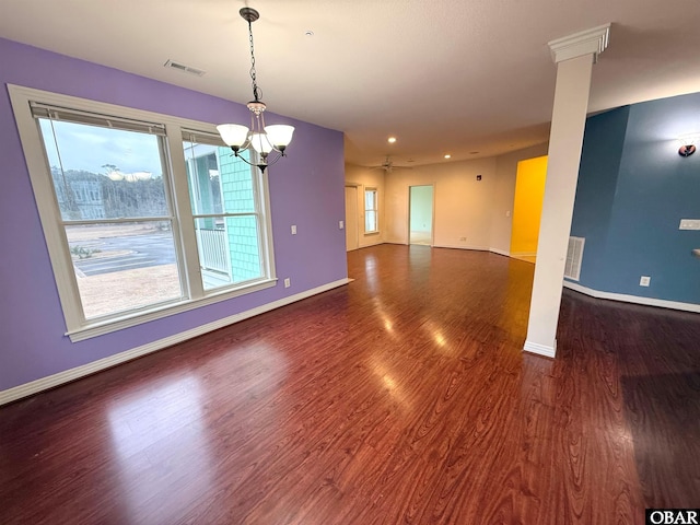 spare room with a healthy amount of sunlight, visible vents, dark wood finished floors, and baseboards