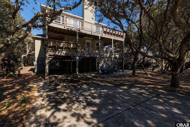 rear view of property with a chimney, stairway, and a porch