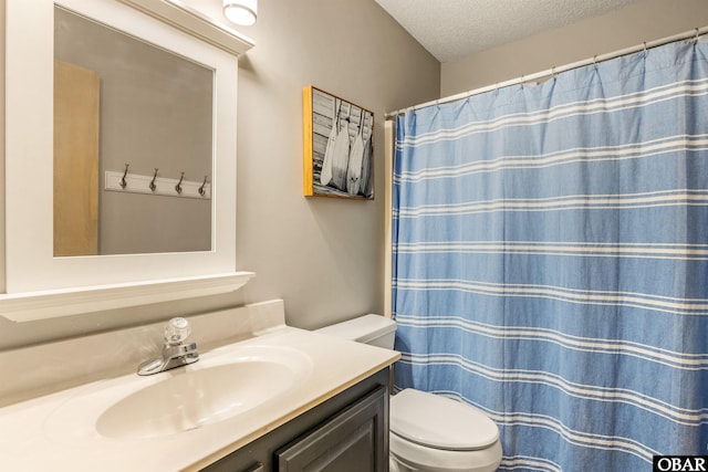 full bath with a textured ceiling, curtained shower, vanity, and toilet