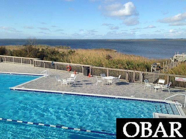 pool with a patio area, fence, and a water view