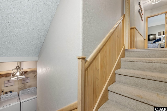 staircase featuring a textured wall, washing machine and clothes dryer, and a barn door