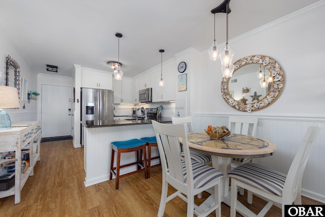 5515 S Virginia Dare Trl Unit B-3, Nags Head, NC 27959 - dining space with light wood-style flooring, a wainscoted wall, and ornamental molding