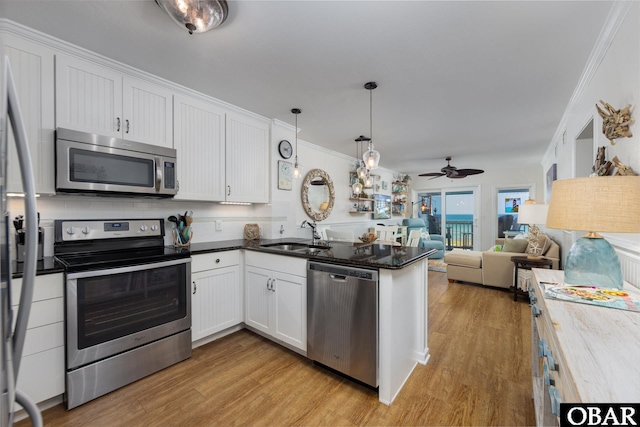 5515 S Virginia Dare Trl Unit B-3, Nags Head, NC 27959 - kitchen featuring stainless steel appliances, a peninsula, ceiling fan, ornamental molding, and white cabinetry