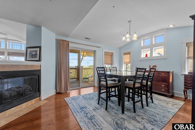 100F Mercedes Ct Unit F, Grandy, NC 27939 - dining area featuring lofted ceiling, healthy amount of natural light, a tiled fireplace, and wood finished floors