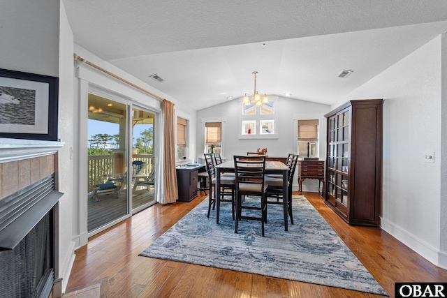 100F Mercedes Ct Unit F, Grandy, NC 27939 - dining space with vaulted ceiling, a fireplace, a chandelier, wood finished floors, and baseboards