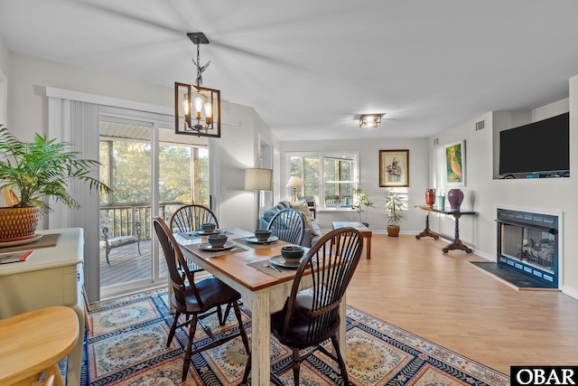 dining room featuring visible vents, a notable chandelier, wood finished floors, a fireplace, and baseboards