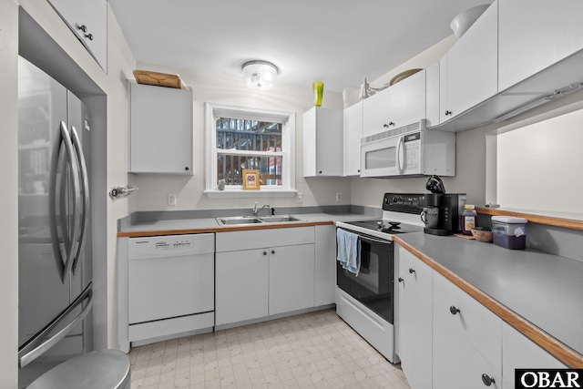 kitchen featuring light floors, white appliances, white cabinets, and a sink