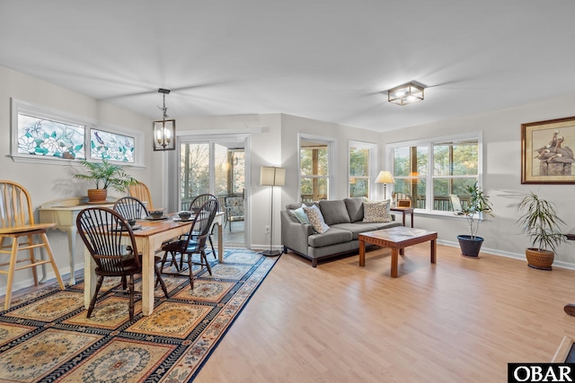 dining room with a wealth of natural light, baseboards, a notable chandelier, and wood finished floors