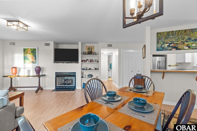 dining room with visible vents, a fireplace with flush hearth, and wood finished floors