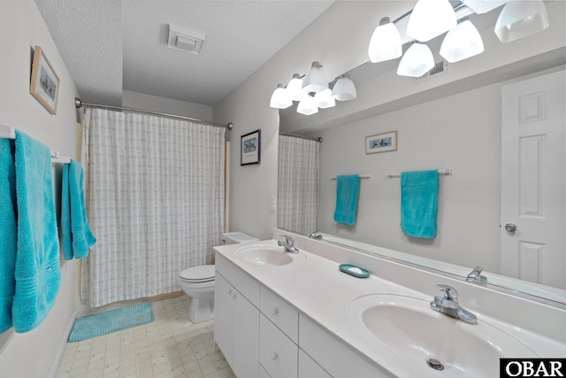 full bathroom featuring a textured ceiling, double vanity, toilet, and a sink