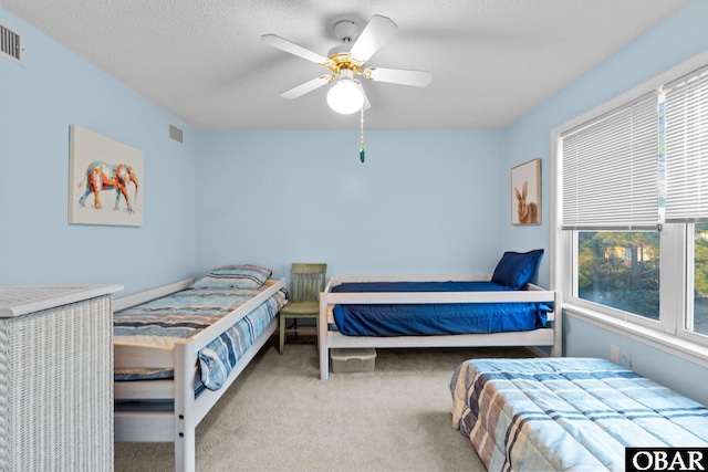 carpeted bedroom featuring visible vents, a textured ceiling, and ceiling fan