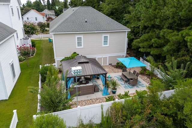 rear view of property with a fenced backyard, outdoor lounge area, a gazebo, a yard, and roof with shingles