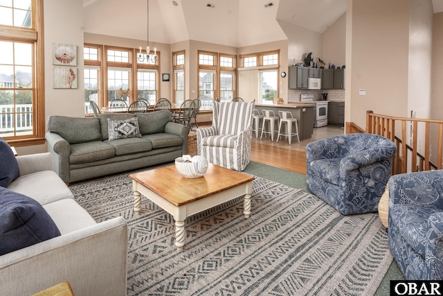 living area featuring a chandelier, high vaulted ceiling, and wood finished floors