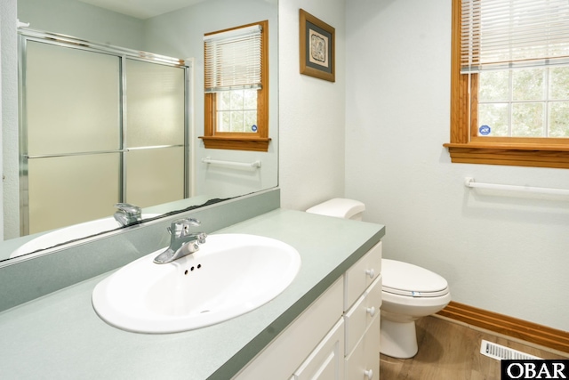 bathroom featuring wood finished floors, plenty of natural light, an enclosed shower, and vanity