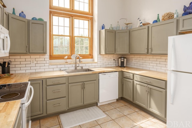 kitchen featuring light tile patterned floors, wooden counters, decorative backsplash, a sink, and white appliances