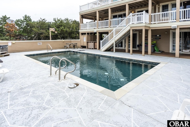 view of swimming pool with stairs, a fenced in pool, and a patio