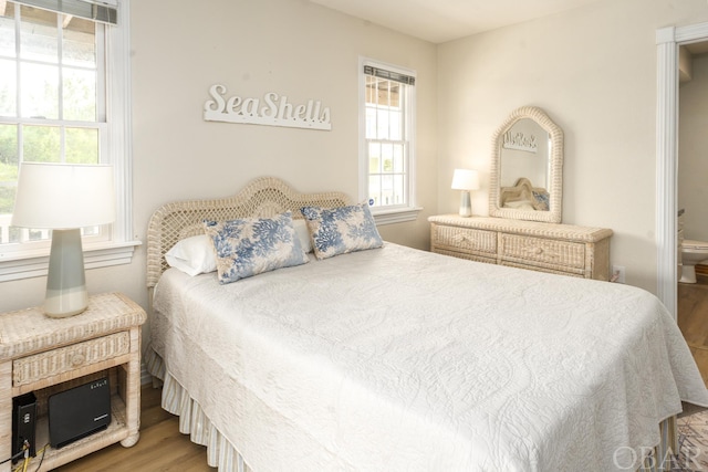 bedroom with ensuite bath and wood finished floors