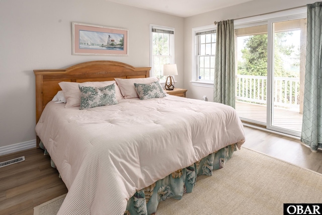 bedroom featuring access to exterior, baseboards, visible vents, and wood finished floors