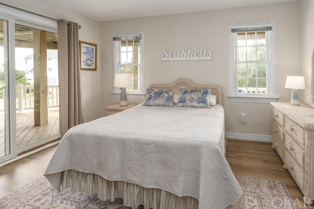 bedroom with access to outside, light wood finished floors, multiple windows, and baseboards