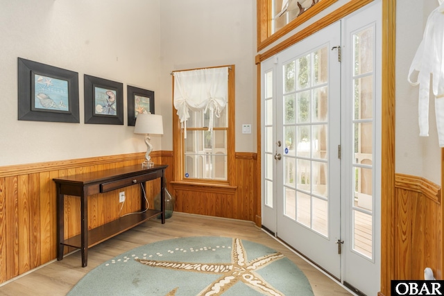 doorway featuring wainscoting, wood finished floors, and wooden walls