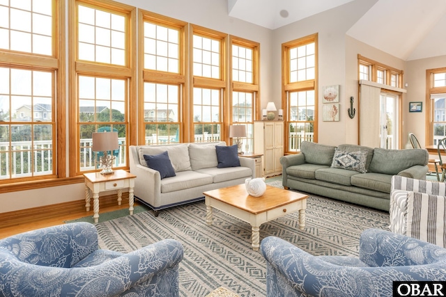 living area with a towering ceiling, baseboards, and wood finished floors