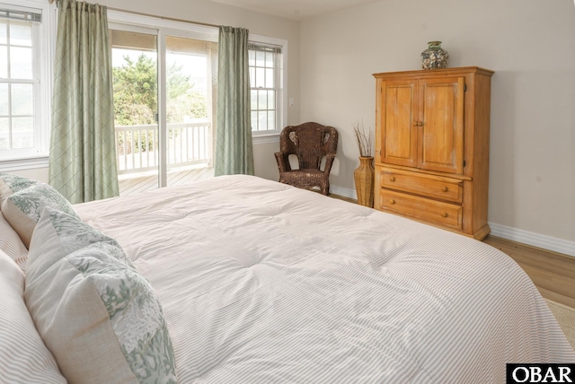 bedroom with access to exterior, light wood-style flooring, and baseboards