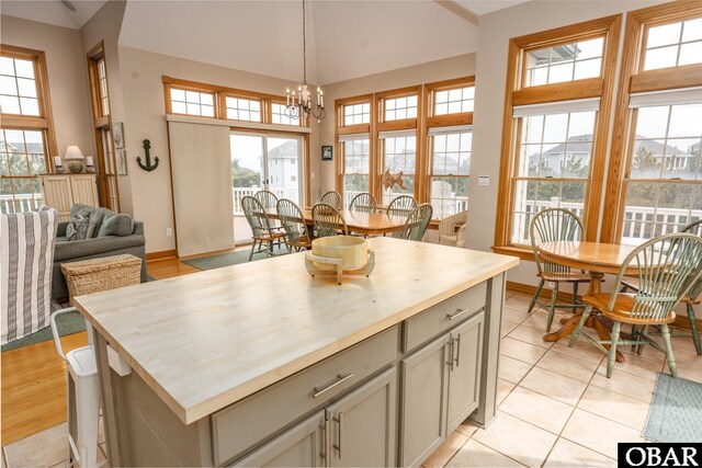 kitchen with baseboards, a kitchen island, hanging light fixtures, gray cabinetry, and a chandelier