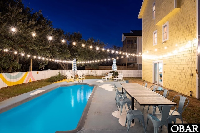 pool at twilight with outdoor dining space, a patio area, a fenced backyard, and a fenced in pool