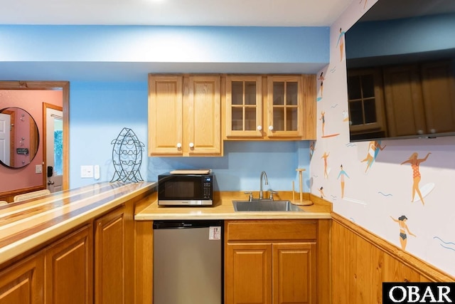 kitchen with brown cabinetry, glass insert cabinets, light countertops, stainless steel dishwasher, and a sink