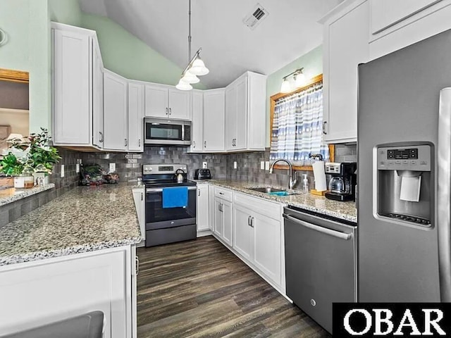 kitchen featuring appliances with stainless steel finishes, white cabinetry, a sink, and tasteful backsplash