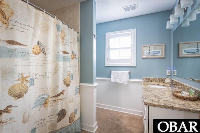 full bath featuring curtained shower, wainscoting, vanity, and visible vents