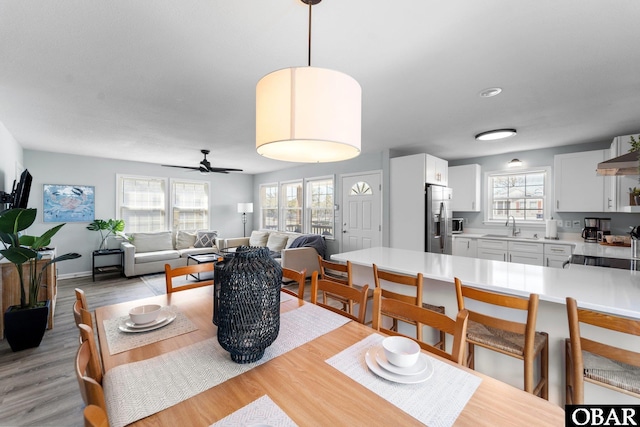 dining space featuring light wood-style floors, baseboards, and a ceiling fan