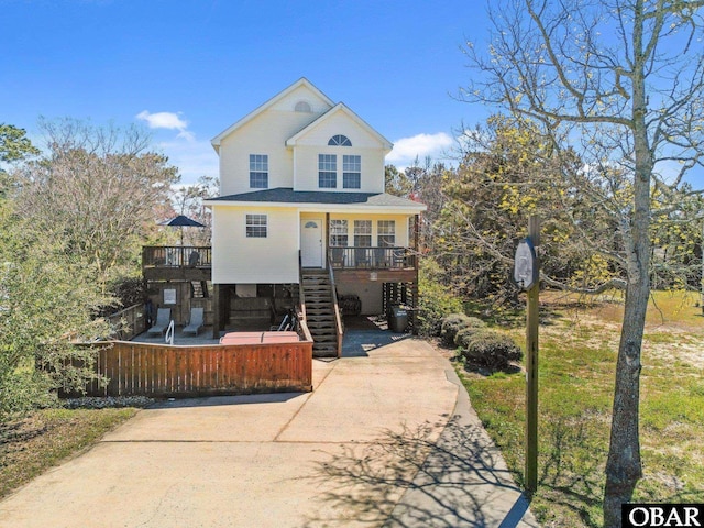 view of front facade featuring driveway, covered porch, and stairway