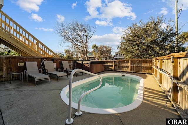 view of pool featuring a fenced in pool, a patio area, a fenced backyard, and a hot tub