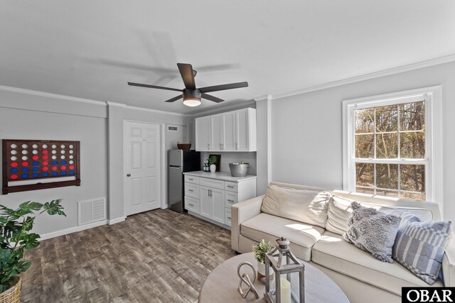 living room featuring ceiling fan, wood finished floors, visible vents, and crown molding