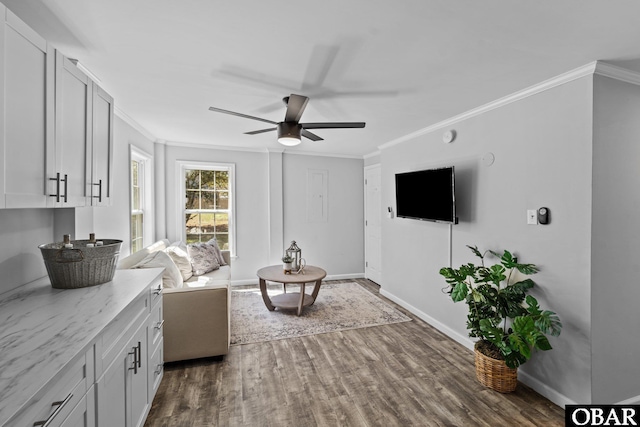 living area featuring dark wood-style floors, ceiling fan, baseboards, and crown molding