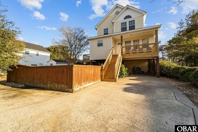 view of front of home featuring covered porch, fence, a garage, driveway, and stairs