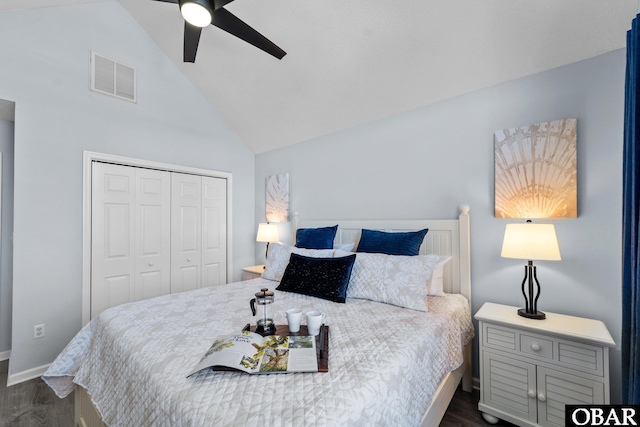 bedroom featuring dark wood-style floors, lofted ceiling, a closet, visible vents, and a ceiling fan