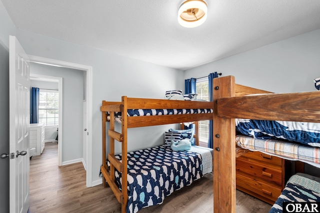 bedroom with multiple windows, wood finished floors, and baseboards