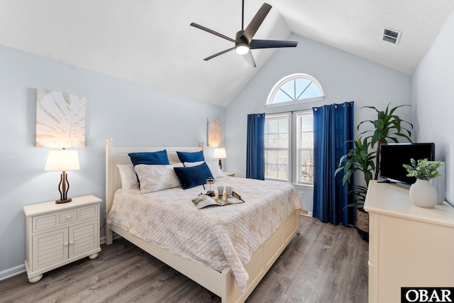 bedroom with ceiling fan, visible vents, vaulted ceiling, and wood finished floors