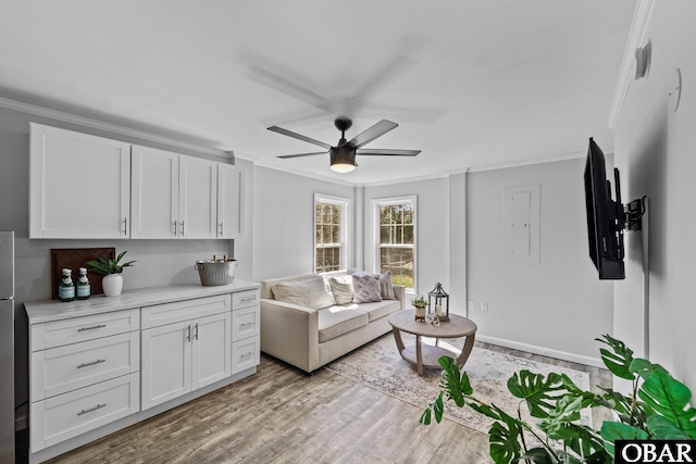 living area featuring ornamental molding, ceiling fan, and light wood-style flooring