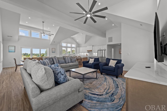 living area with high vaulted ceiling, visible vents, and light wood finished floors