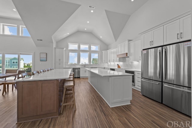 kitchen featuring white cabinets, appliances with stainless steel finishes, a kitchen breakfast bar, dark wood-style flooring, and a center island