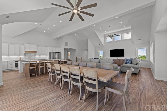 dining space featuring light wood-type flooring, ceiling fan, and high vaulted ceiling