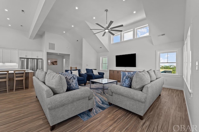 living room with baseboards, visible vents, a ceiling fan, a towering ceiling, and wood finished floors