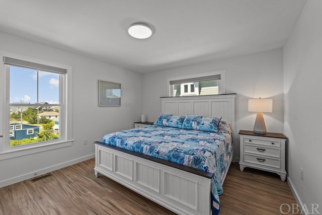 bedroom with dark wood finished floors, visible vents, and baseboards