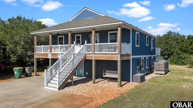 1017 Corolla Dr Lot 52, Corolla, NC 27927 - coastal home featuring a porch, roof with shingles, stairs, central air condition unit, and a front lawn