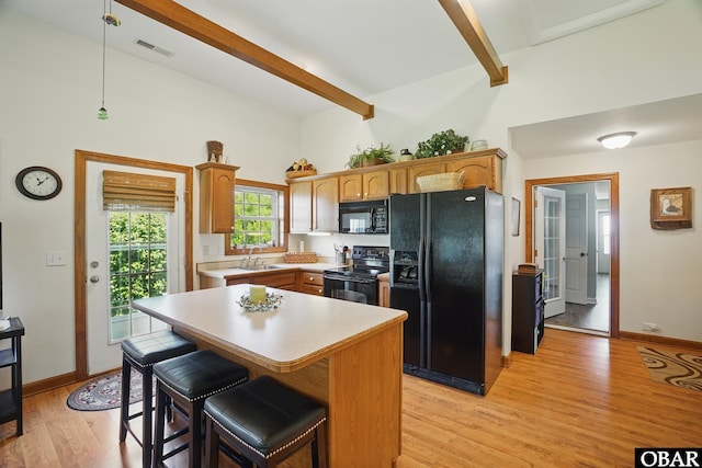 184 Tabernacle Ln, Aydlett, NC 27916 - kitchen featuring black appliances, beamed ceiling, light wood-style flooring, light countertops, and hanging light fixtures