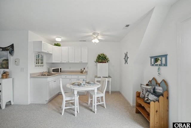 184 Tabernacle Ln, Aydlett, NC 27916 - kitchen featuring white microwave, ceiling fan, light countertops, white cabinets, and light colored carpet